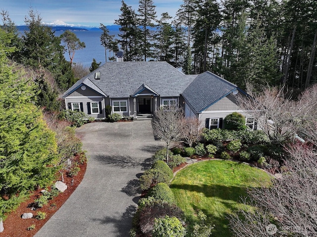view of front of home featuring driveway, a water view, and a front lawn