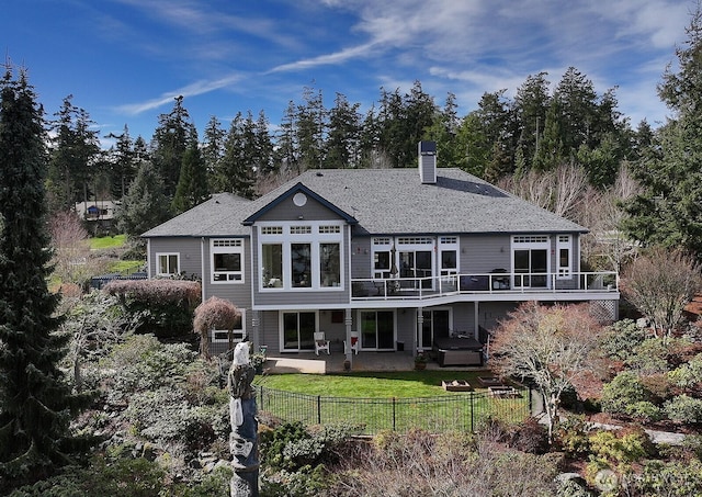 back of house featuring a chimney, a fenced backyard, a deck, a shingled roof, and a yard