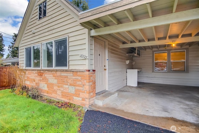 doorway to property with fence and a carport