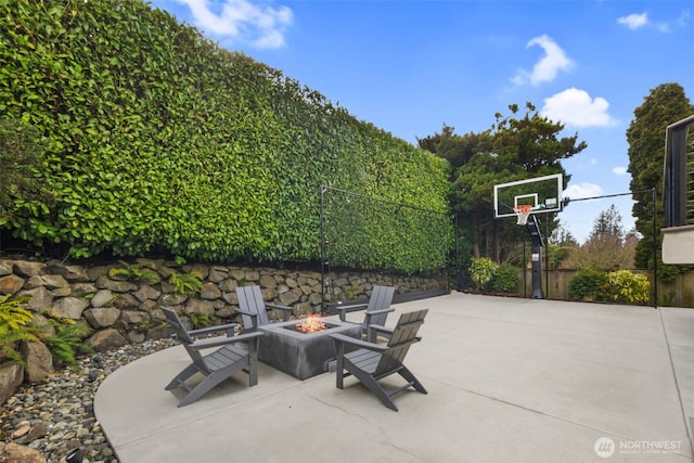 view of patio featuring basketball hoop, an outdoor fire pit, and fence