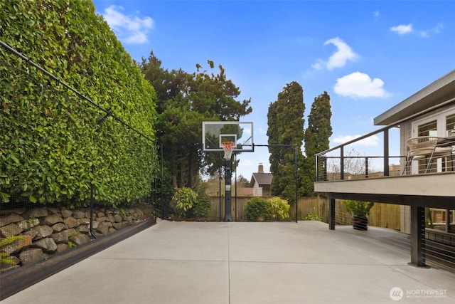 view of basketball court with basketball hoop and fence