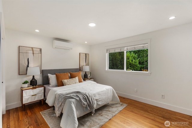 bedroom with recessed lighting, a wall mounted air conditioner, baseboards, and wood finished floors