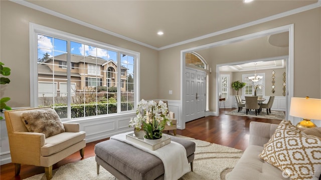 living room with plenty of natural light, a notable chandelier, crown molding, and wood finished floors