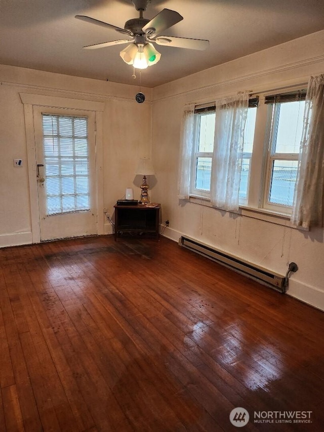 interior space with dark wood-style floors, baseboards, baseboard heating, and a ceiling fan