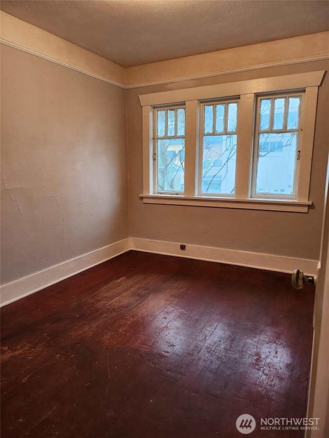 spare room with dark wood-style flooring and baseboards