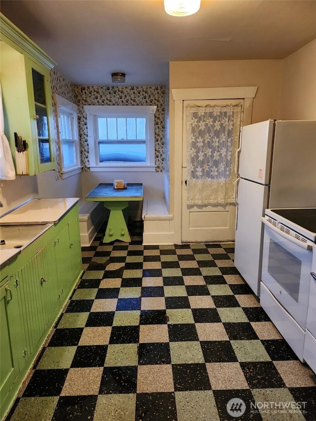 kitchen featuring dark floors, light countertops, electric range, and green cabinets