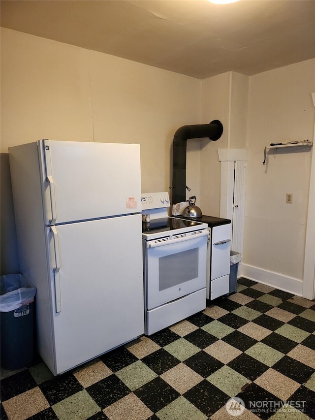 kitchen featuring white appliances, dark floors, and baseboards