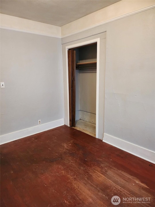 unfurnished bedroom with a closet, baseboards, and wood finished floors