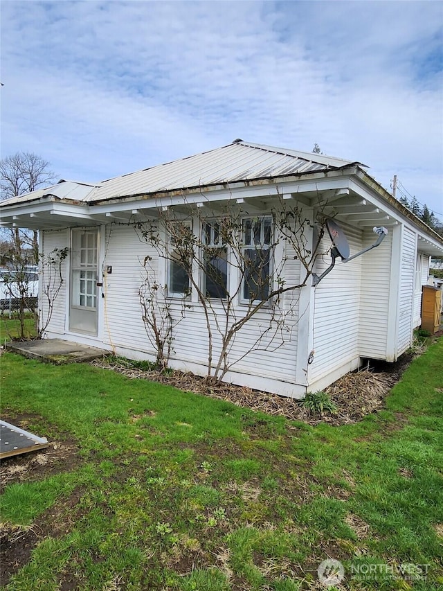 back of house with metal roof and a lawn