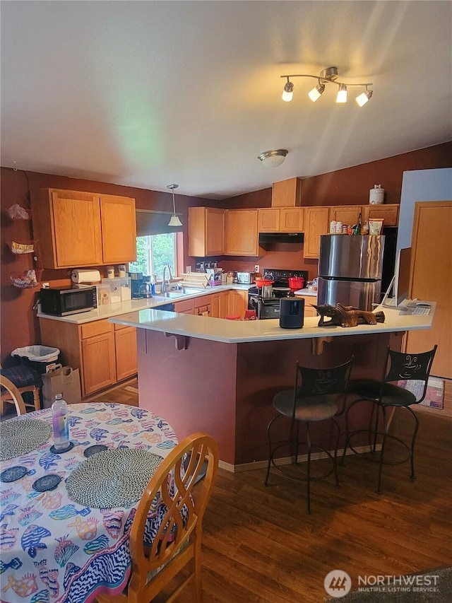 kitchen with under cabinet range hood, light countertops, electric stove, freestanding refrigerator, and decorative light fixtures