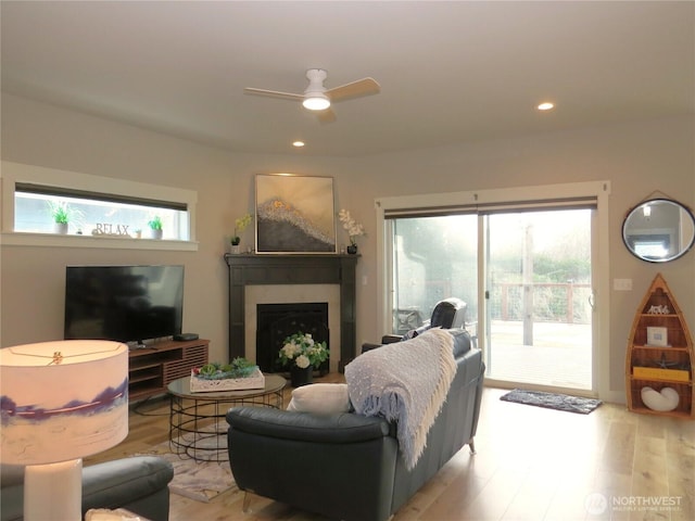 living area featuring light wood finished floors, recessed lighting, a fireplace, and a ceiling fan