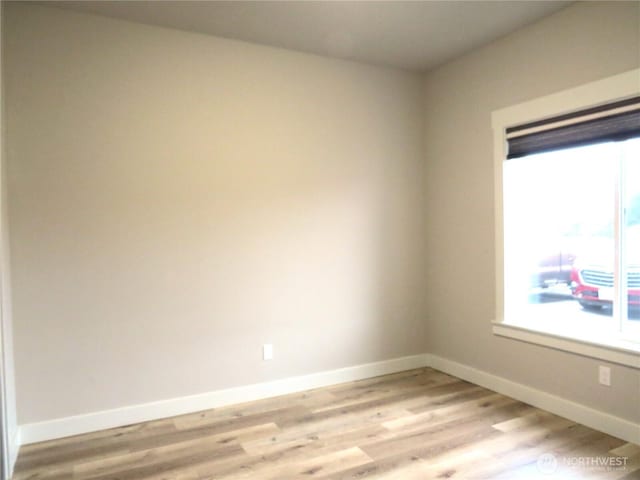 unfurnished room with light wood-type flooring and baseboards