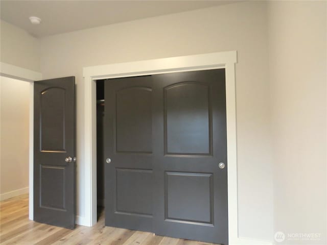 unfurnished bedroom with light wood-type flooring, baseboards, and a closet