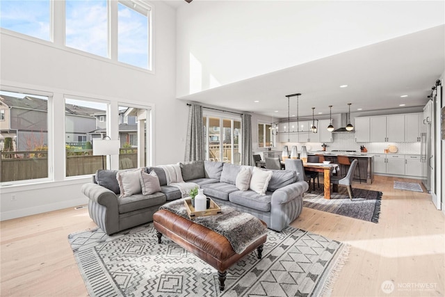 living area with light wood-style floors, plenty of natural light, and a high ceiling