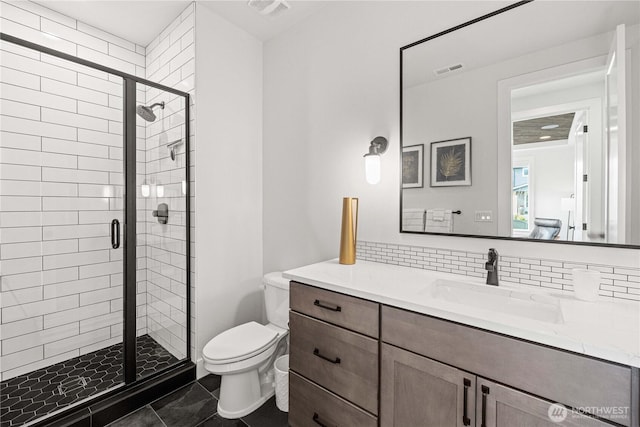 bathroom featuring toilet, visible vents, vanity, a shower stall, and decorative backsplash