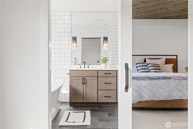 ensuite bathroom featuring a freestanding bath, tile walls, connected bathroom, and vanity