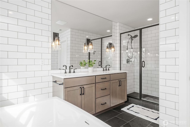 bathroom with a shower stall, double vanity, a sink, and tile patterned floors