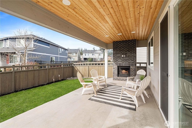 view of patio / terrace with an outdoor brick fireplace, a residential view, and fence