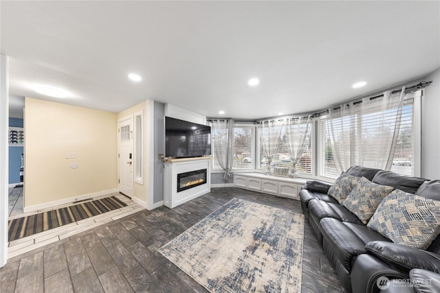 unfurnished living room with recessed lighting, baseboards, dark wood-style flooring, and a glass covered fireplace