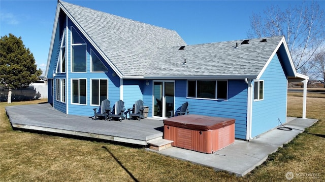 back of house featuring a deck, roof with shingles, a lawn, and a hot tub