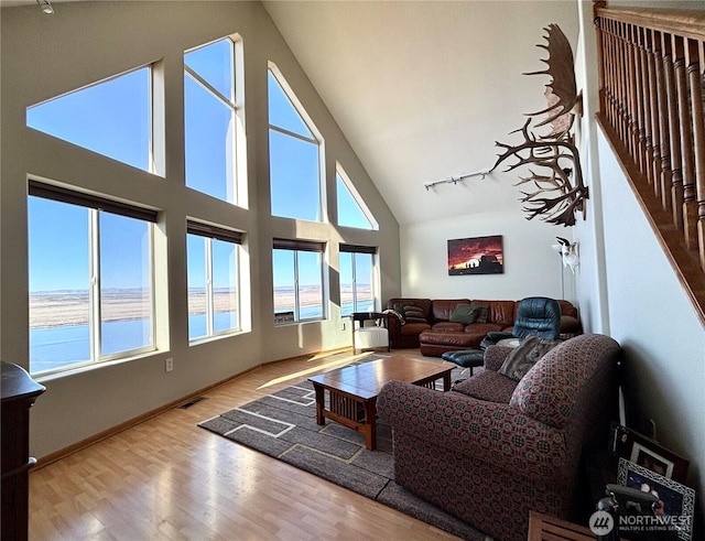 living room featuring baseboards, visible vents, wood finished floors, high vaulted ceiling, and track lighting