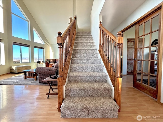 stairway featuring high vaulted ceiling and wood finished floors