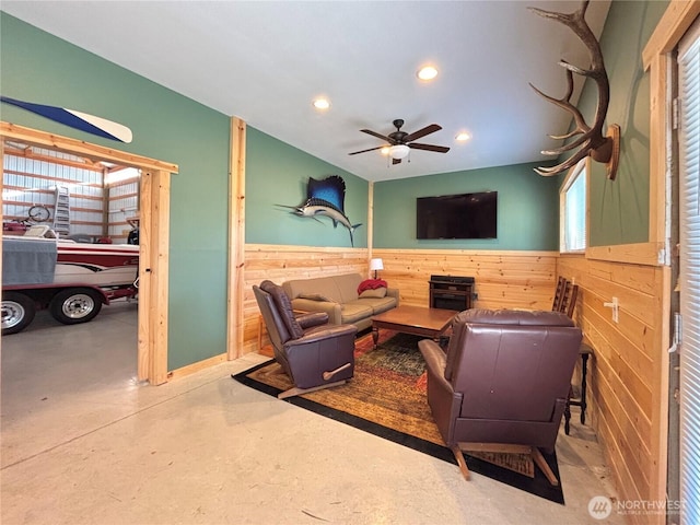 living room with finished concrete flooring, recessed lighting, a ceiling fan, wainscoting, and wood walls