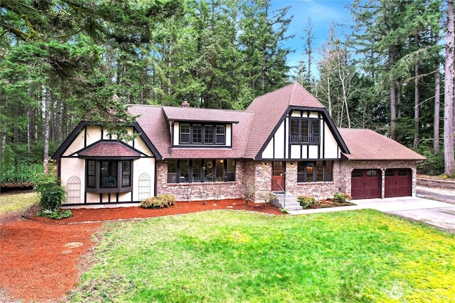 tudor house featuring a garage, a shingled roof, concrete driveway, a chimney, and a front yard