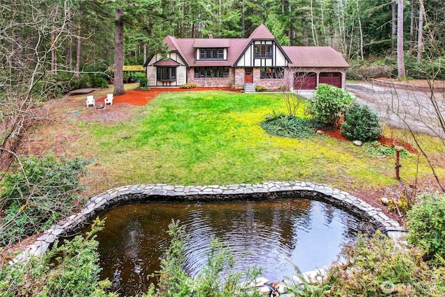 view of front of house featuring a garage, a front yard, and a wooded view