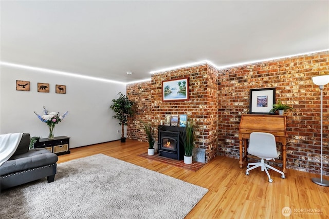 living area with brick wall, wood finished floors, and a wood stove