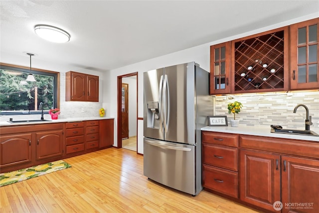 kitchen with a sink, light countertops, light wood-type flooring, and stainless steel fridge