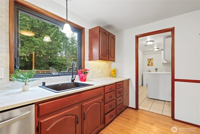 kitchen featuring dishwasher, light countertops, a sink, and decorative backsplash