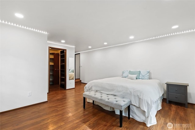 bedroom with baseboards, wood finished floors, a spacious closet, a closet, and recessed lighting