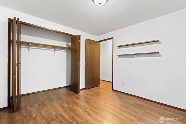 unfurnished bedroom featuring a closet, wood finished floors, and baseboards