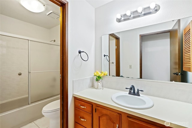 bathroom with visible vents, toilet, combined bath / shower with glass door, vanity, and tile patterned flooring