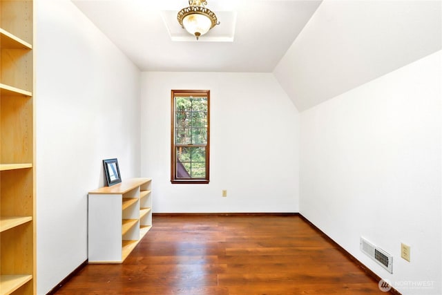 additional living space with visible vents, vaulted ceiling, baseboards, and wood finished floors