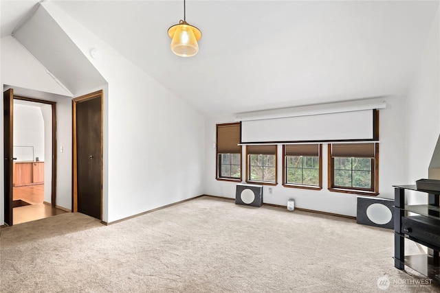 unfurnished living room with carpet, vaulted ceiling, and baseboards