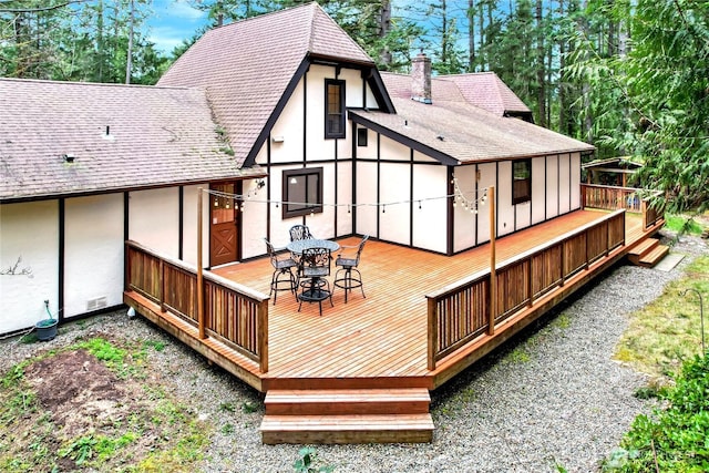 rear view of property featuring a shingled roof, a chimney, and stucco siding