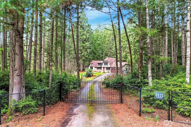 view of gate featuring fence and a view of trees