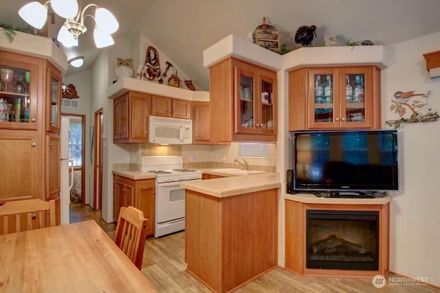 kitchen featuring light wood-style flooring, white appliances, a sink, light countertops, and glass insert cabinets