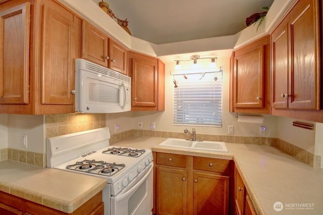 kitchen featuring light countertops, white appliances, brown cabinetry, and a sink