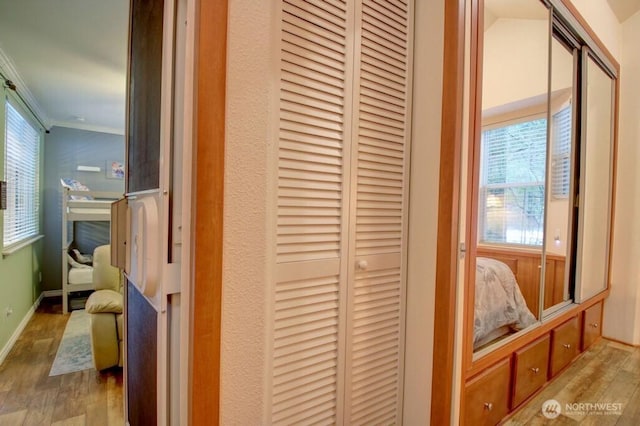 corridor featuring crown molding, baseboards, and wood finished floors