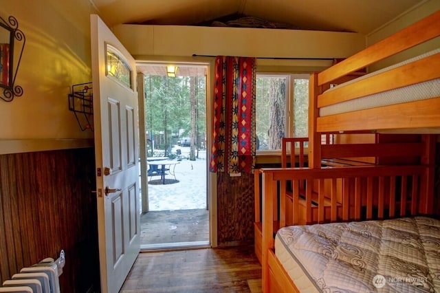 bedroom featuring lofted ceiling, access to outside, wood finished floors, and radiator