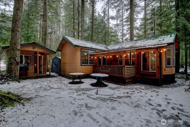 back of property featuring a porch and metal roof