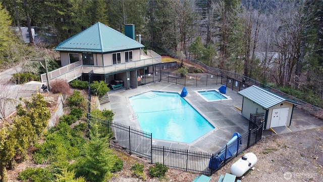 pool with fence, stairs, a forest view, a patio area, and a hot tub