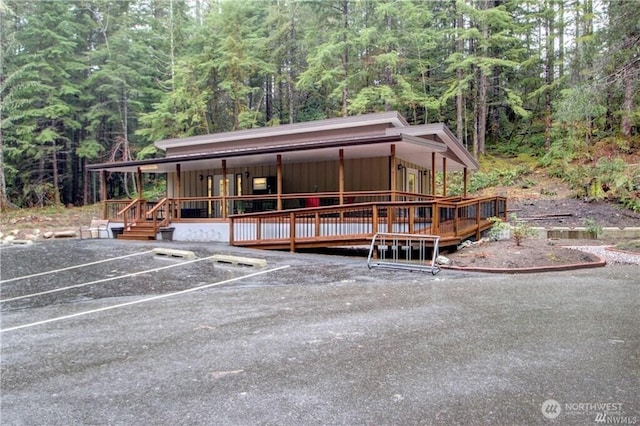 view of front of home featuring uncovered parking, board and batten siding, and a wooded view