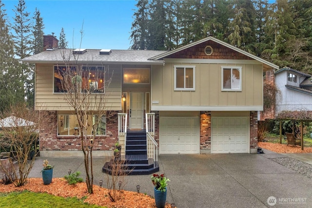 raised ranch with concrete driveway, brick siding, a chimney, and an attached garage