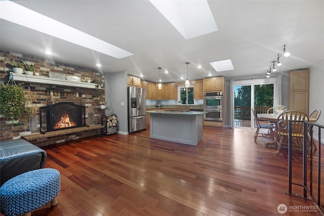 kitchen with stainless steel appliances, a skylight, a kitchen island, and dark wood-style floors