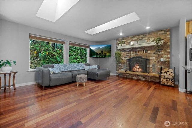 living area featuring wood finished floors, a skylight, a fireplace, and baseboards