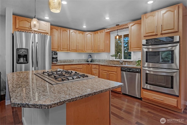 kitchen featuring pendant lighting, stainless steel appliances, a sink, and a center island